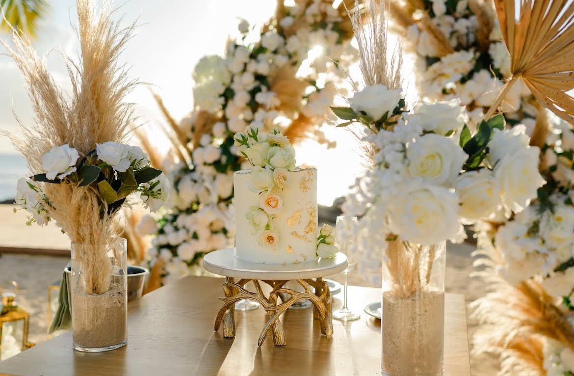 Wedding cake styled with gold leaf, white roses and pampas grass in warm light