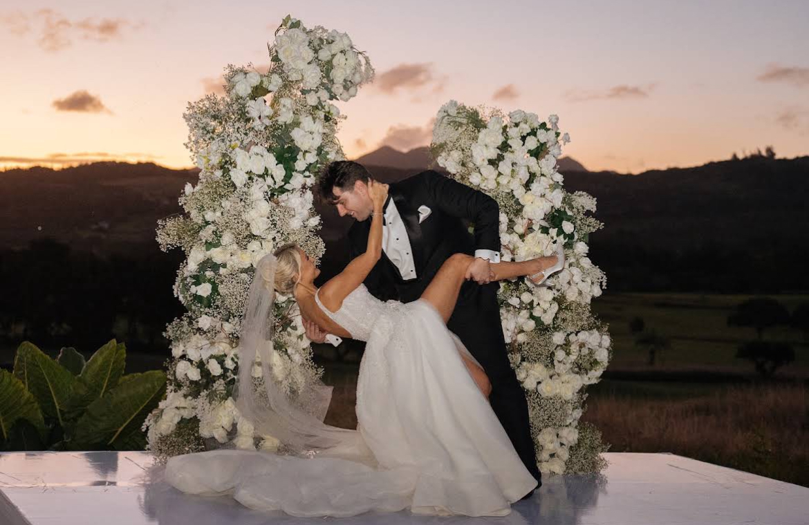 Bride and groom at sunset beneath a white floral arch at a luxury wedding in Mauritius