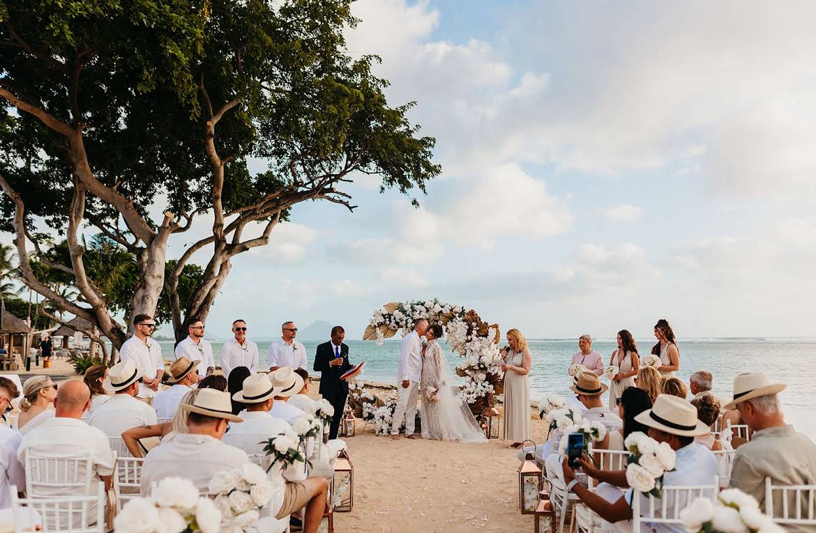 Destination beach wedding ceremony in Mauritius with a white floral arch by the ocean